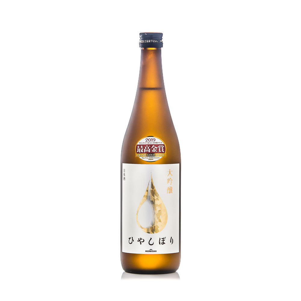 A brown glass bottle of Konishi Gold - Daiginjo sake with a gold and white label featuring Japanese characters and a droplet design, photographed on a white background—Fine Sake Awards winner.