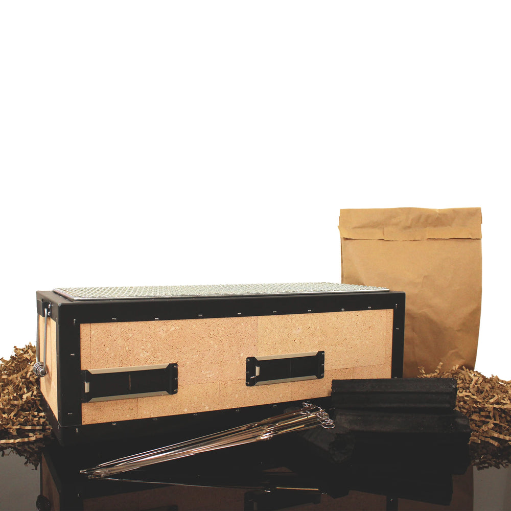 The Konro Grill 54cm Barbecue Set, including a rectangular wooden box with metal accents, a brown paper bag, packing material, and long metal skewers, is displayed on a black surface—ideal for Japanese BBQ.