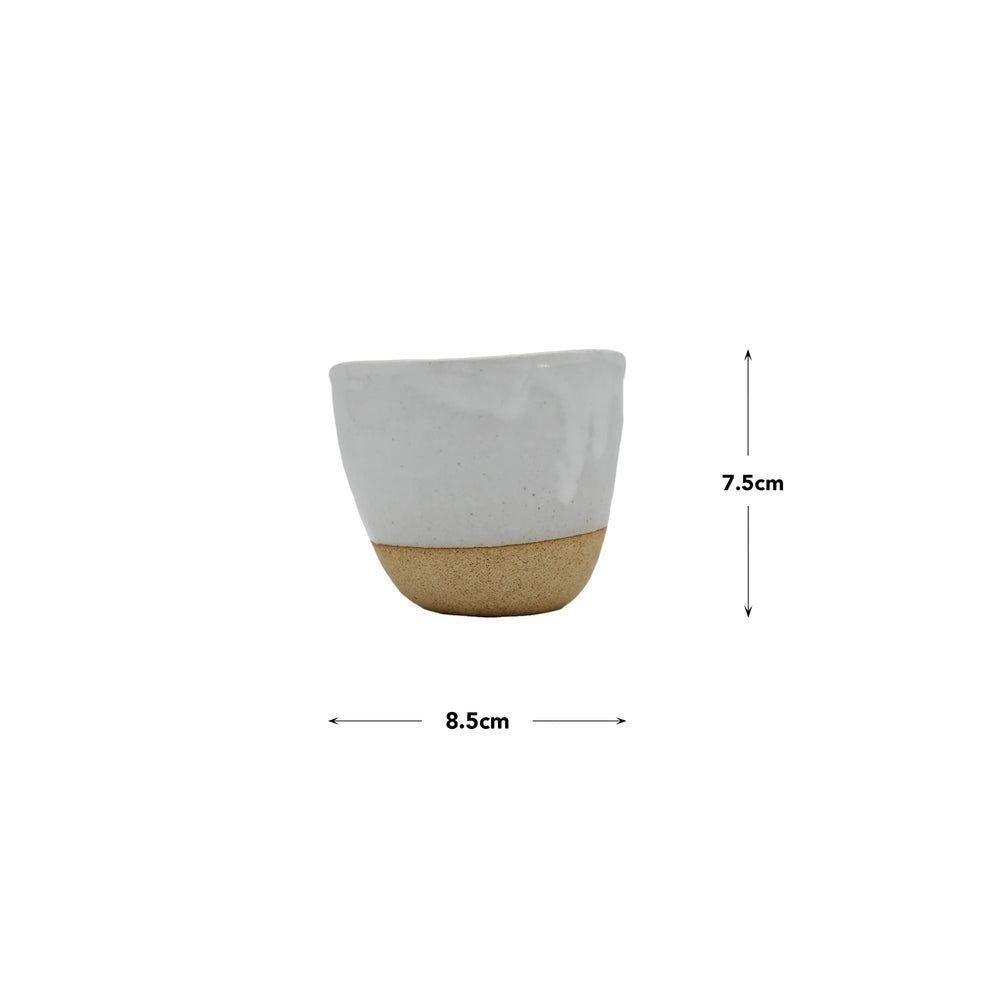 The Lopsided Mug - White And Bisque is a small ceramic cup with a white top and beige earthenware base, measuring 8.5 cm wide by 7.5 cm tall, inspired by Japanese craftsmanship, shown on a white background.