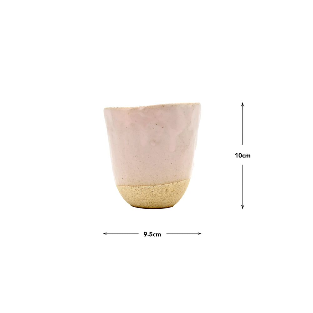 The Lopsided Mug - Pink is a beige and light pink earthenware cup with an uneven rim, measuring 10 cm tall and 9.5 cm wide, inspired by the classic ceramic style of the Marunaka family.
