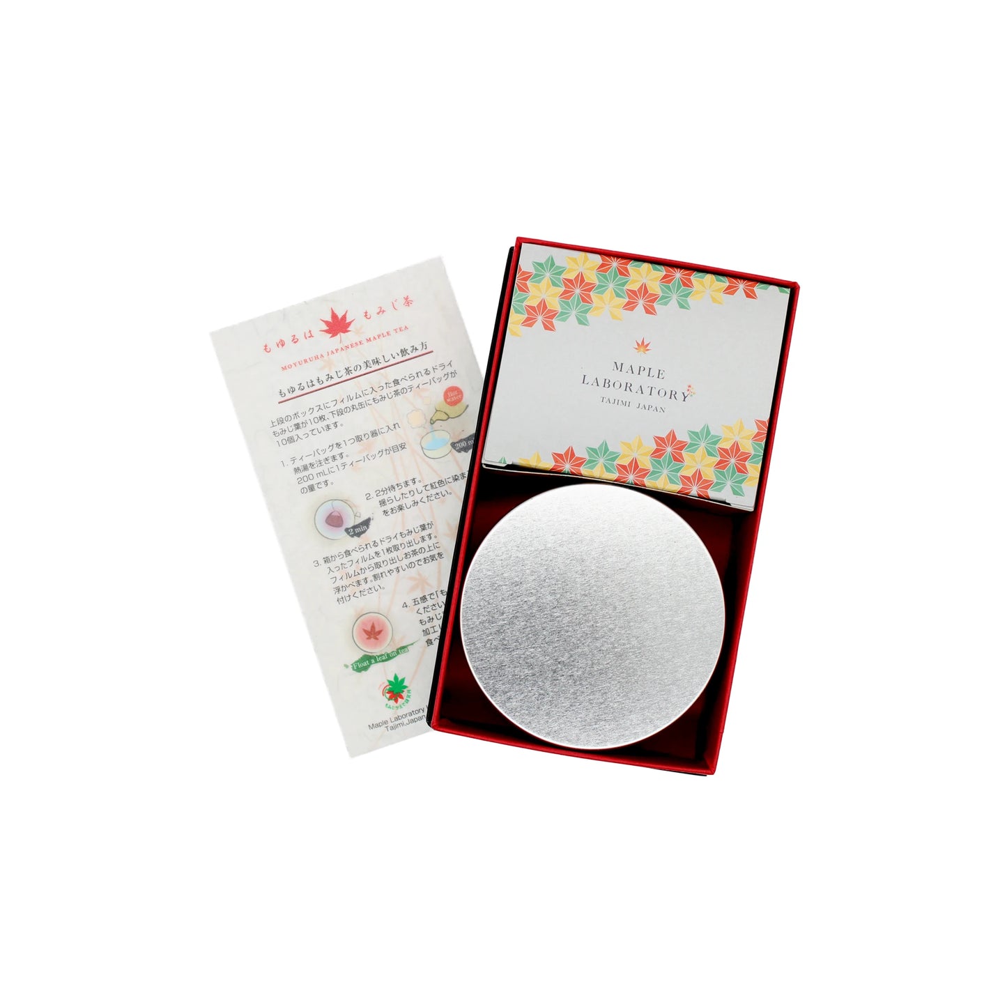 A box containing the Maple Tea Set—10 tea bags and 10 dried maple leaves for caffeine-free tea—with a floral MAPLE LABORATORY card, a silver circular item, and an illustrated Japanese instruction sheet.