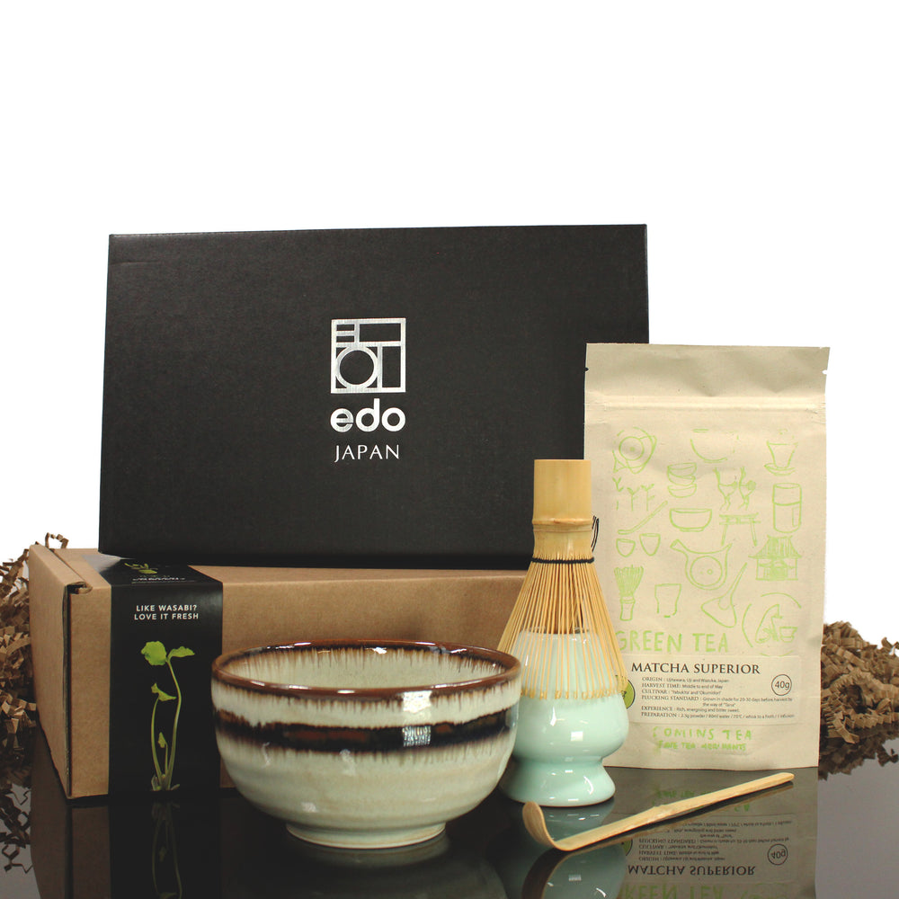 The Matcha Tea Set in Green with Matcha Tea includes a ceramic bowl, bamboo whisk, matcha spoon, superior grade matcha packet, and a gift box with the edo JAPAN logo—all beautifully arranged on a reflective surface.