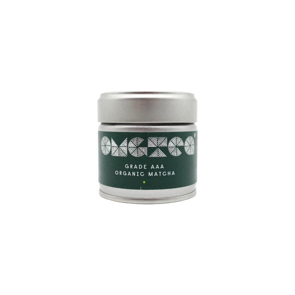 A silver tin labeled AAA Grade Organic Matcha Green Tea – 30g with geometric designs on a green background, displayed against a white backdrop.