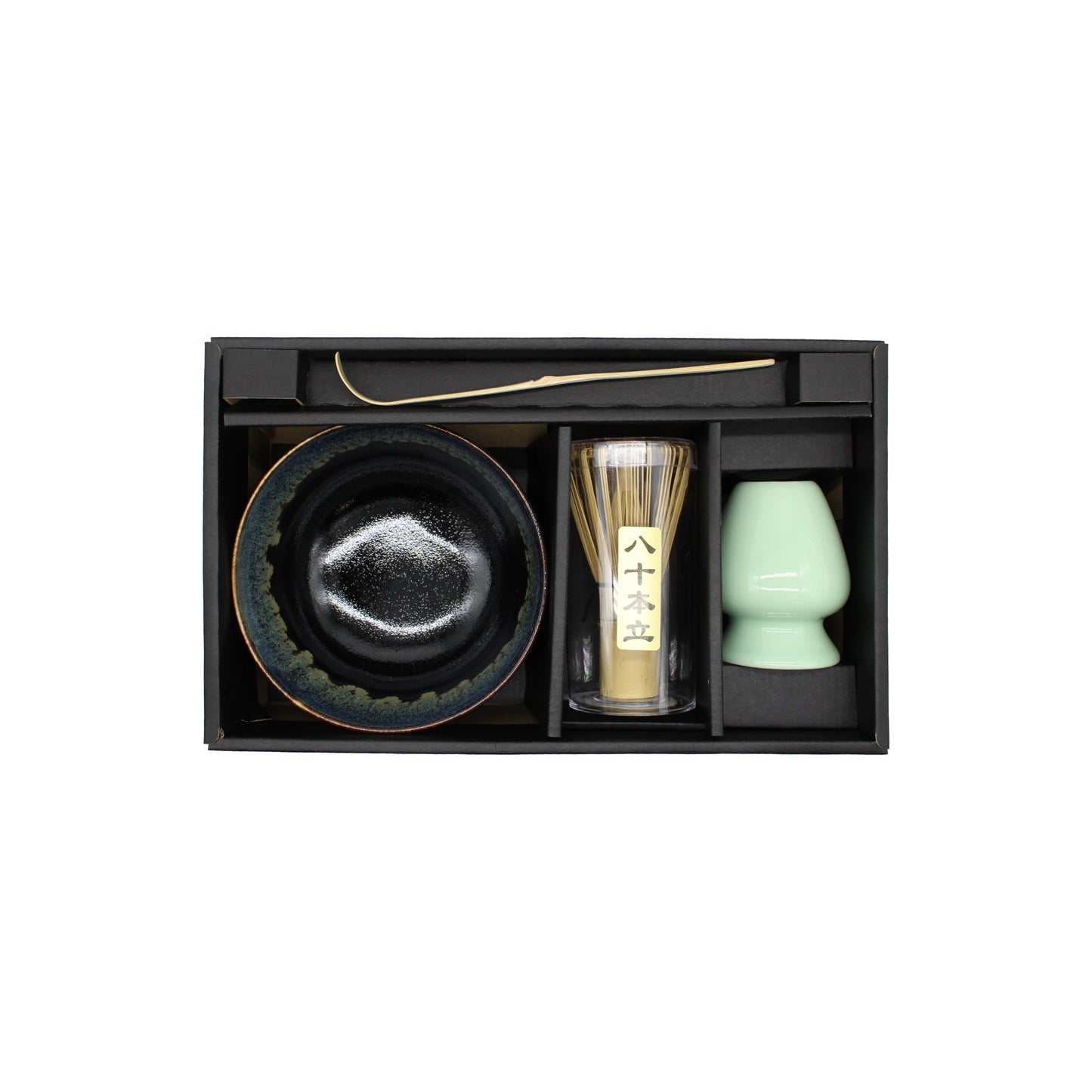 The Matcha Tea Set - Black Cascade includes a black bowl, bamboo whisk, green cup, and metal scoop—everything you need for an authentic Japanese matcha experience in a beautifully arranged gift box.