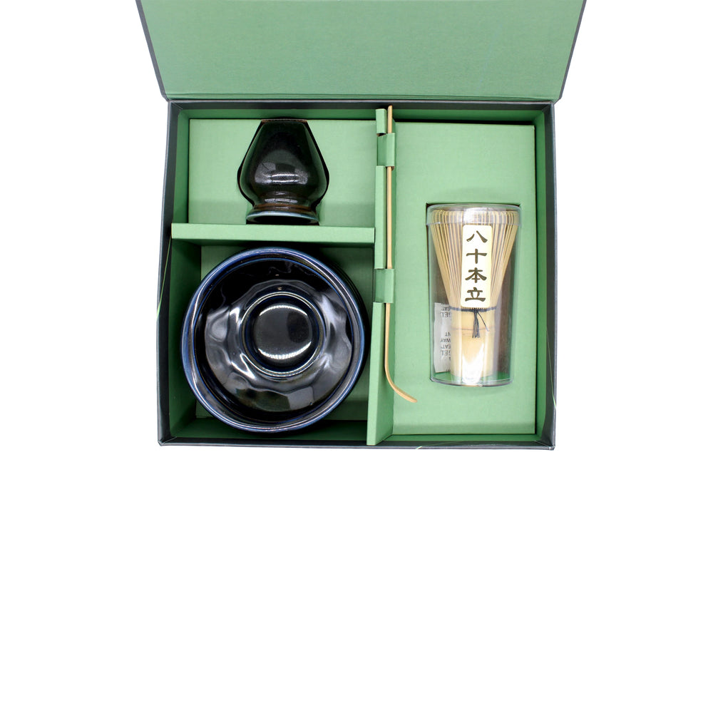 
                  
                    The Matcha Tea Set - Black comes in a green box and includes essentials for a Japanese tea ceremony: a black bowl, bamboo whisk, tea scoop, tea caddy, and a container with Japanese writing.
                  
                
