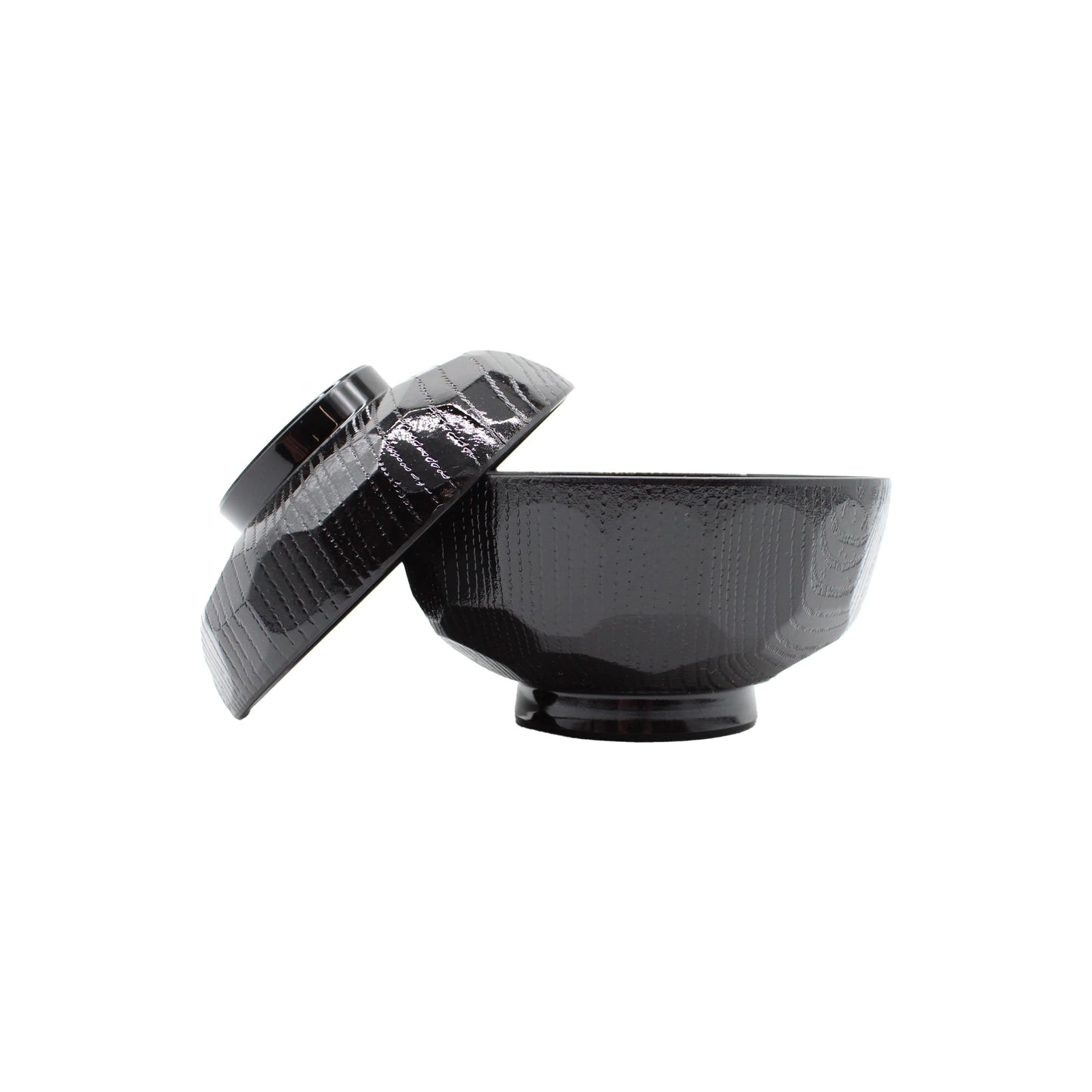 
                  
                    The Miso Bowl With Lid is a black textured bowl and matching lid, both with a faceted design. The lid rests at an angle on the bowl’s edge, evoking traditional Japanese lacquerware style.
                  
                