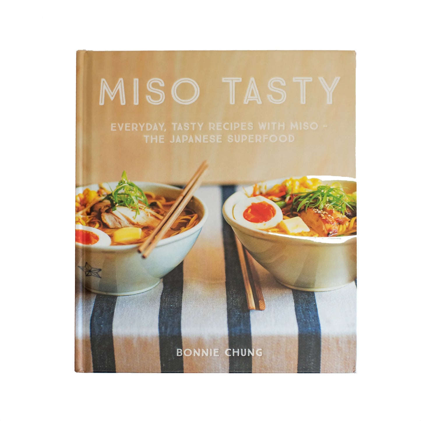 The cover of Miso Tasty: Everyday Recipes with Miso by Bonnie Chung shows two bowls of soup with chopsticks and garnishes on a striped cloth, highlighting delicious miso recipes and the umami-rich taste of miso.