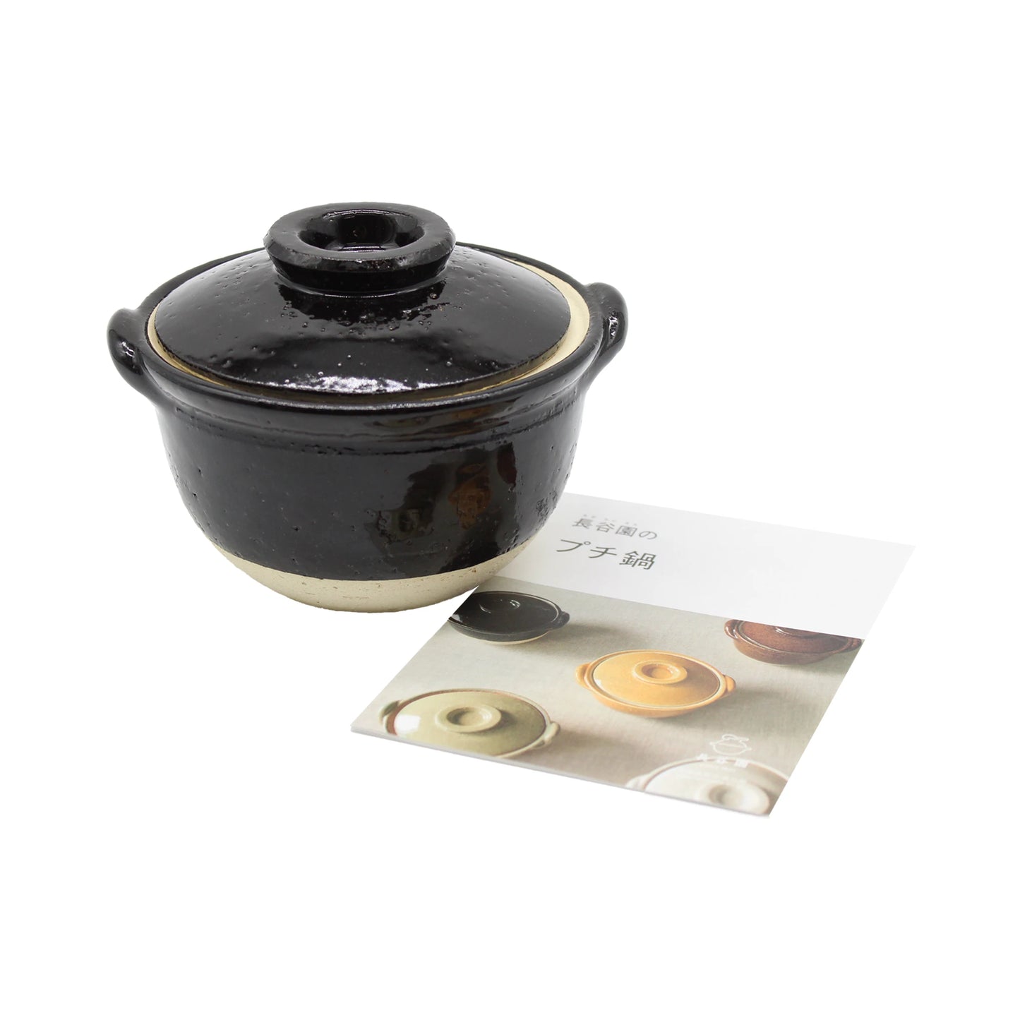 
                  
                    A Mini Donabe Pot - Black, a small Iga ware ceramic vessel with handles and a lid, sits next to a booklet displaying images of similar Japanese earthenware pots in various colors on a white background.
                  
                