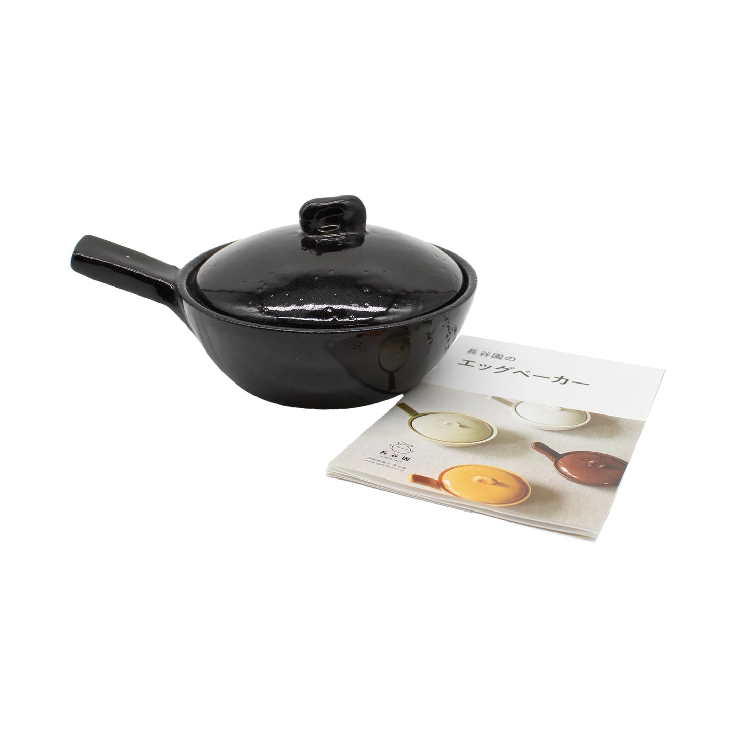 
                  
                    A Mini Baking Dish - Black with a handle and lid, styled like a Japanese ceramic pot, sits beside a folded instruction booklet displaying images of similar mini baking dishes in various colors.
                  
                