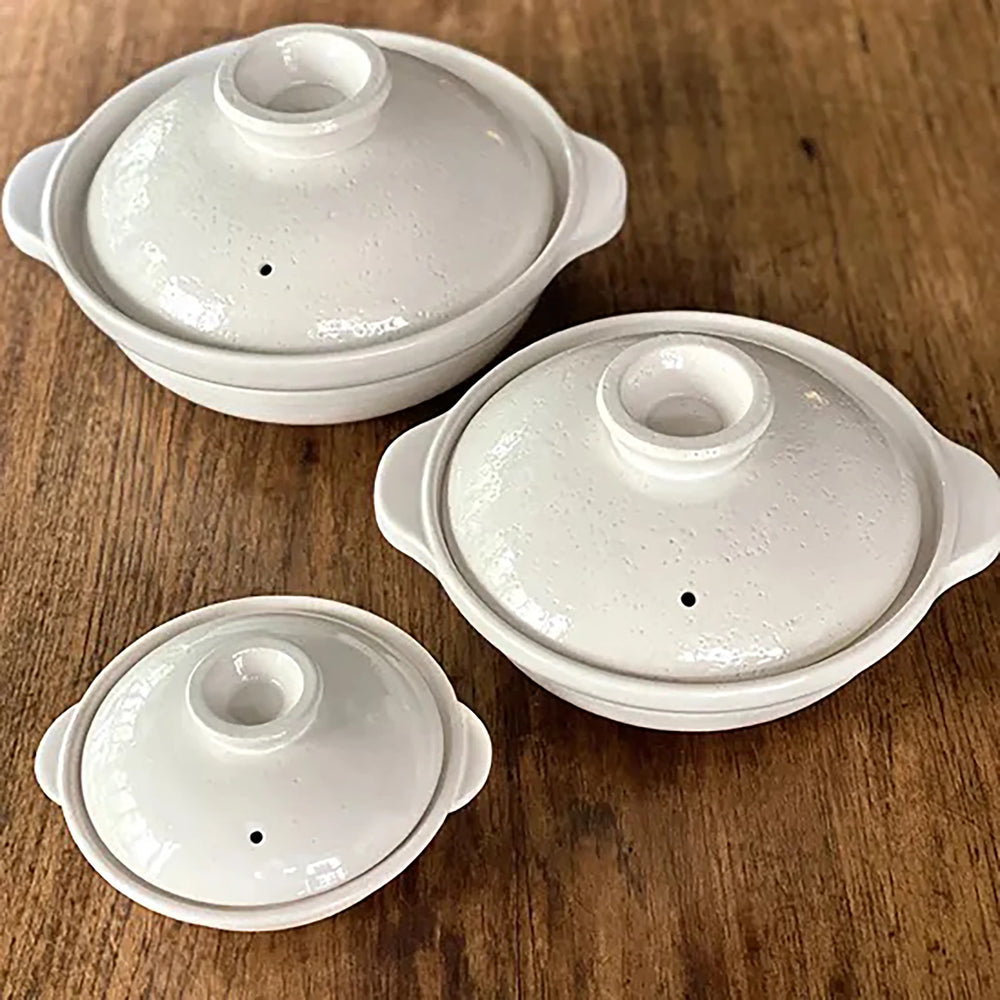 
                  
                    Three Iga Clay Cooking Pots - White Glaze, each with a lid and handles, rest on a wooden surface—ideal for preparing authentic Japanese hotpot.
                  
                