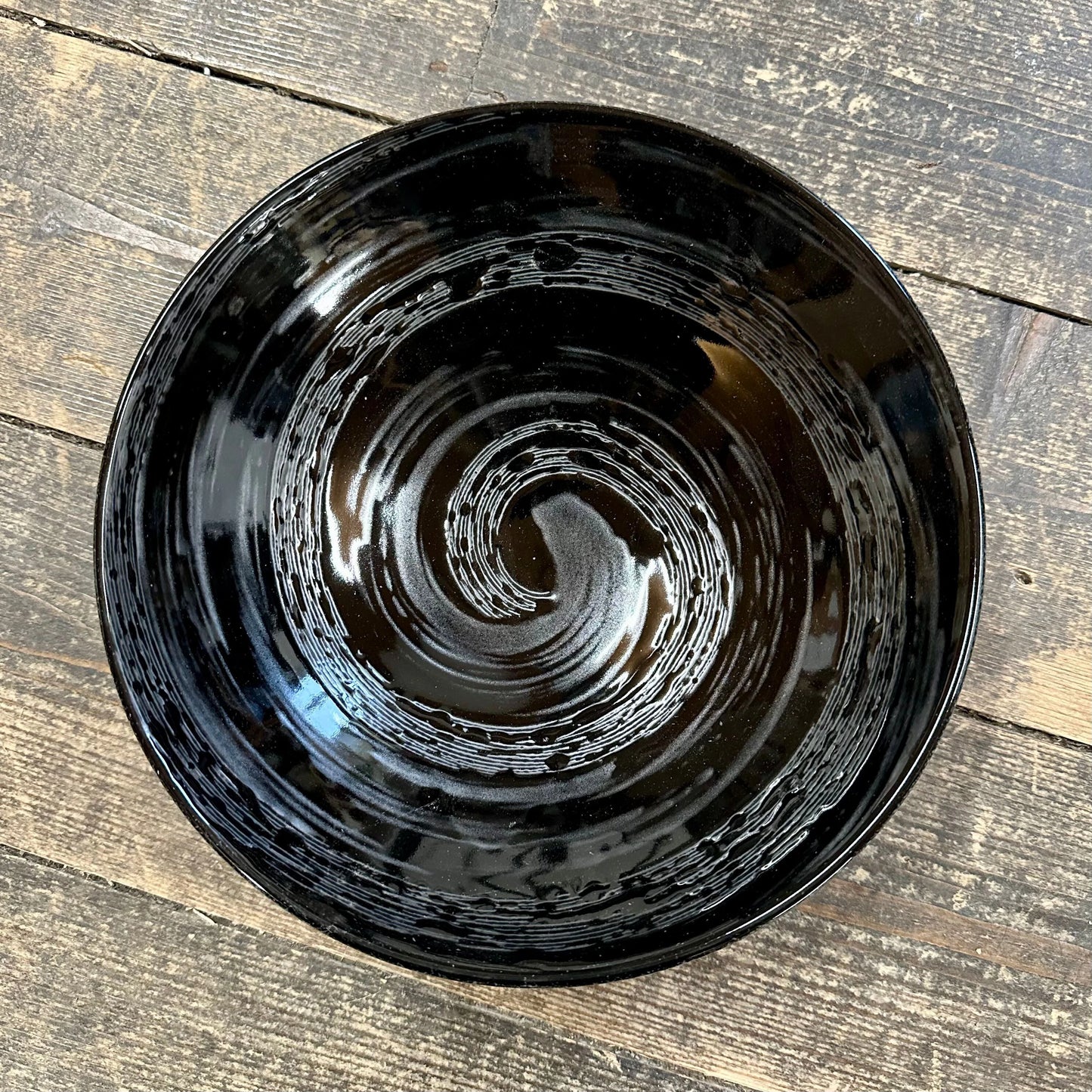 
                  
                    The Ramen Bowl - Gunmetal Swirl is a glossy black handcrafted bowl with a gunmetal swirl design, displayed on a rustic wooden surface and highlighting exquisite Japanese craftsmanship.
                  
                