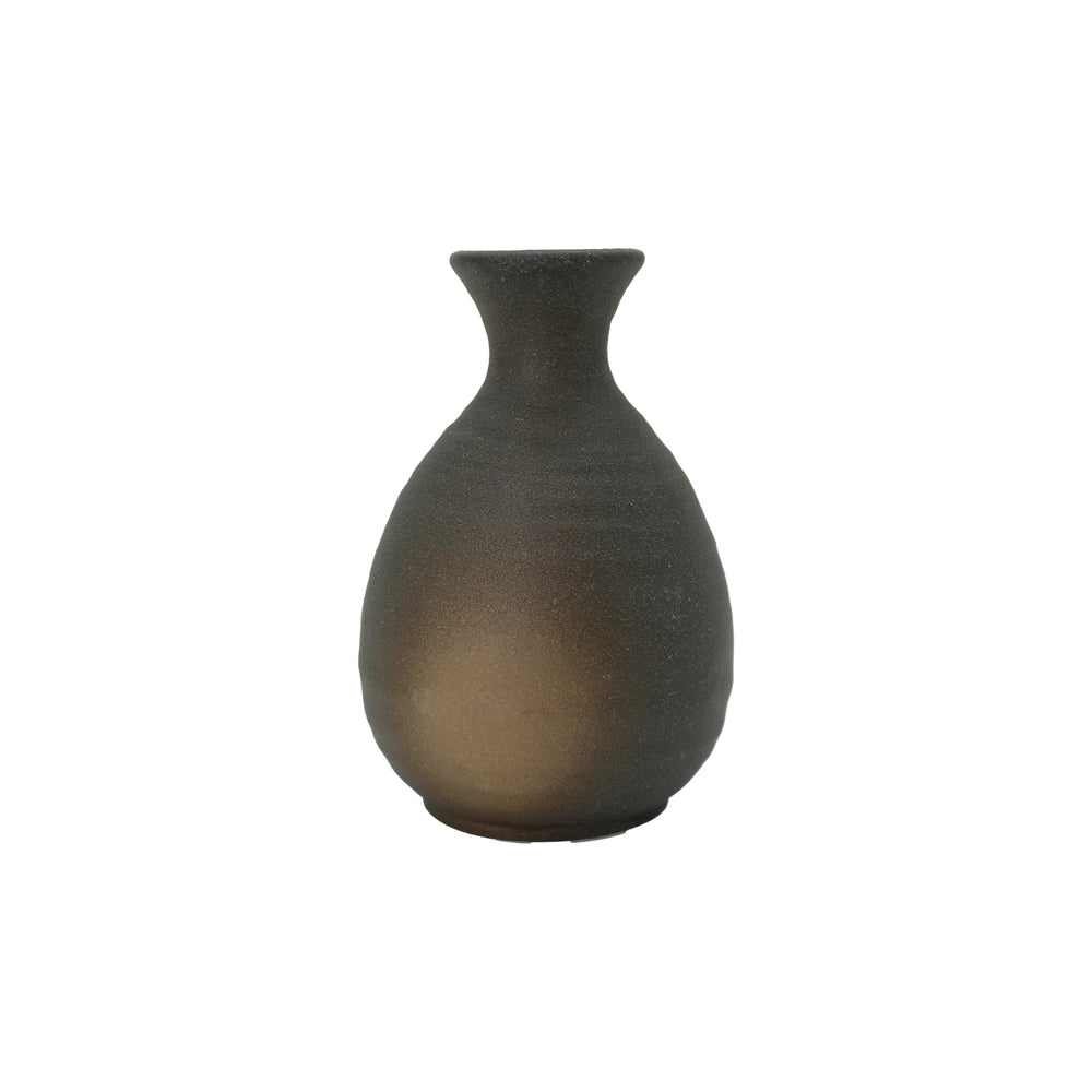 The Sake Carafe - Black Bizen features a matte, dark finish with a rounded body and narrow, flared neck, inspired by traditional Okayama pottery. Displayed against a white background.