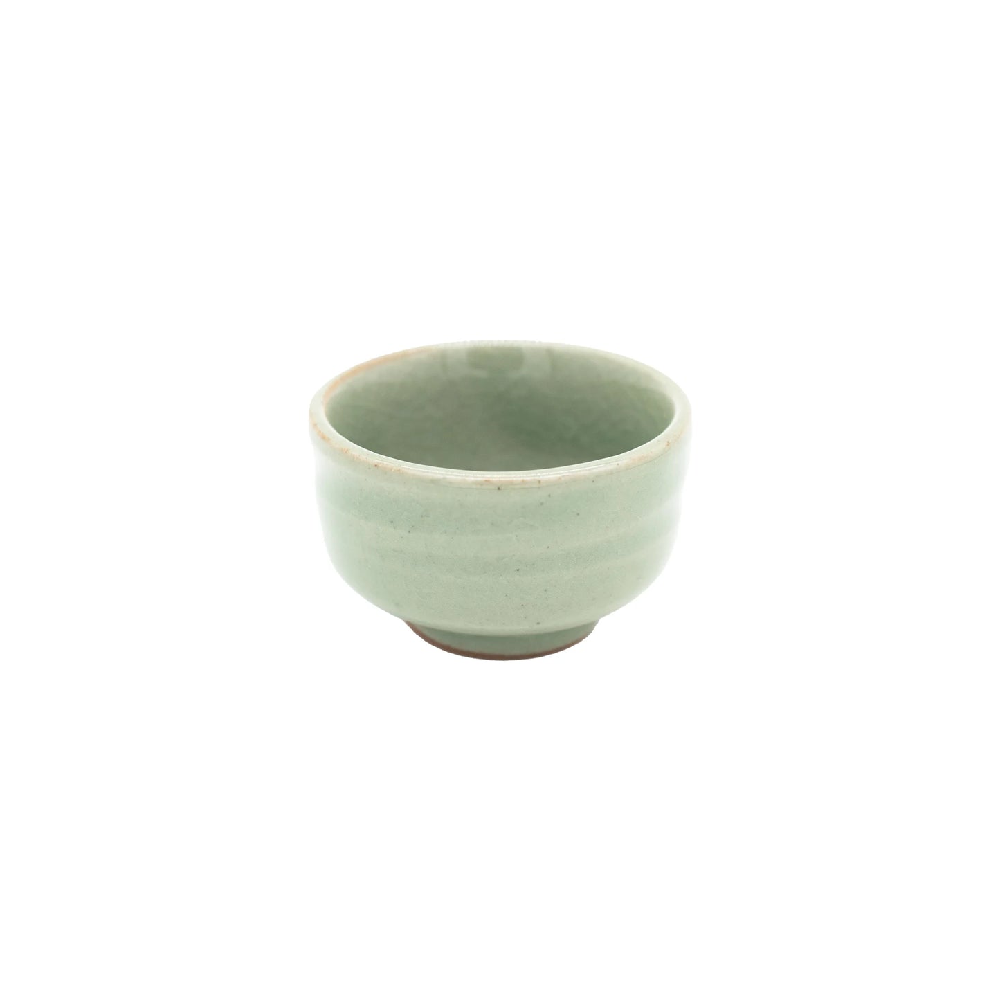 The Sake Cup - Celadon Green is a small, round cup made from Minoyaki porcelain, featuring a light green celadon glaze and a slightly flared rim, displayed on a plain white background.