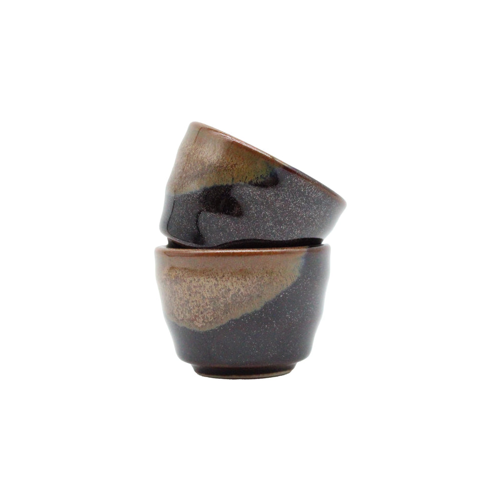 
                  
                    A set of four small Japanese ceramic sake cups with a glossy dark brown and beige glaze—perfect for enjoying Konishi Gold Sake.
                  
                