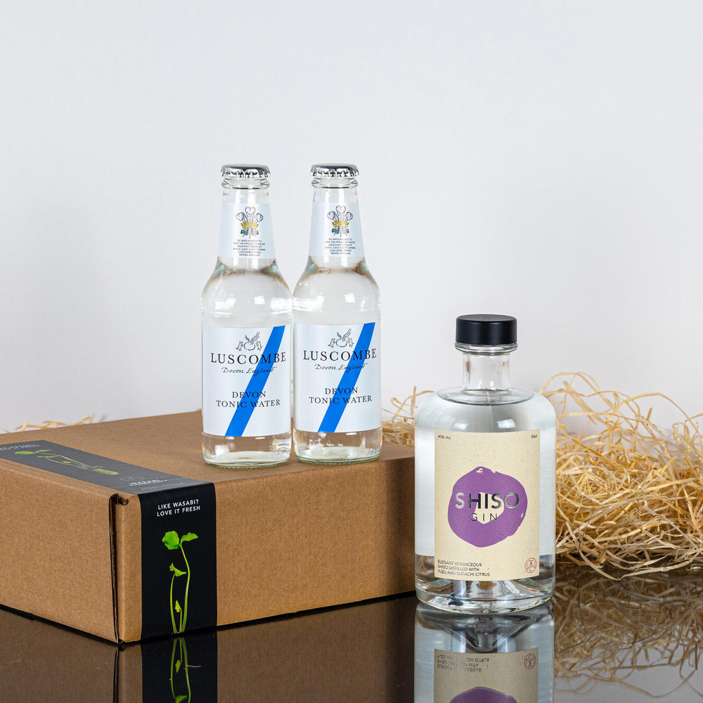 The Shiso Gin & Devon Tonic Water Set, featuring two Luscombe Devon Tonic Waters and a Shiso Gin bottle with Japanese yuzu notes, is displayed in a brown box with straw packaging on a white surface.