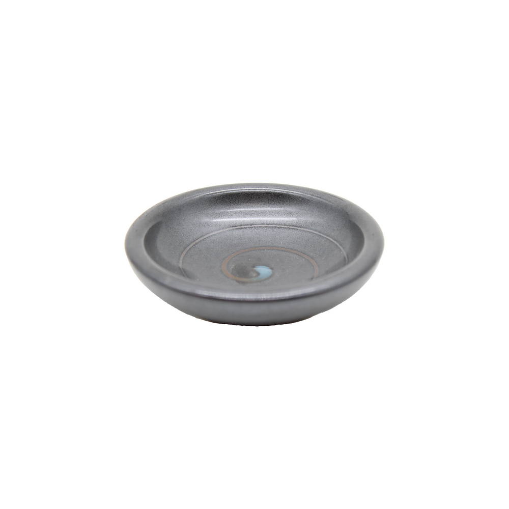 The Soy Sauce Dish - Black Vortex is a small, round, gray ceramic dish with a subtle spiral pattern and slightly raised rim, ideal for serving Japanese pickles, shown on a plain white background.