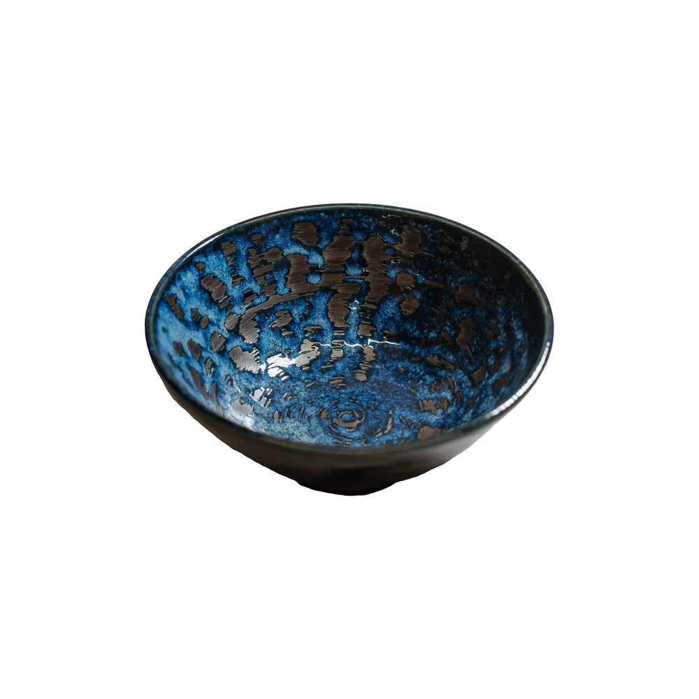 The Udon Bowl - Copper Swirl features a rounded shape with a slightly flared rim and is crafted from Minoyaki porcelain, showcasing a striking blue and black glazed pattern on a white background.