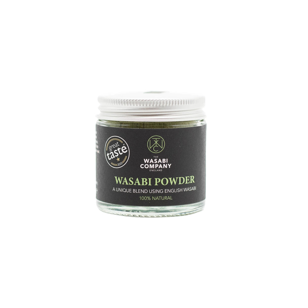 A glass jar of Wasabi Powder - 23g from The Wasabi Company, with a black lid and dark label, is centered on a white background, offering authentic Japanese spicy flavor for your dishes.