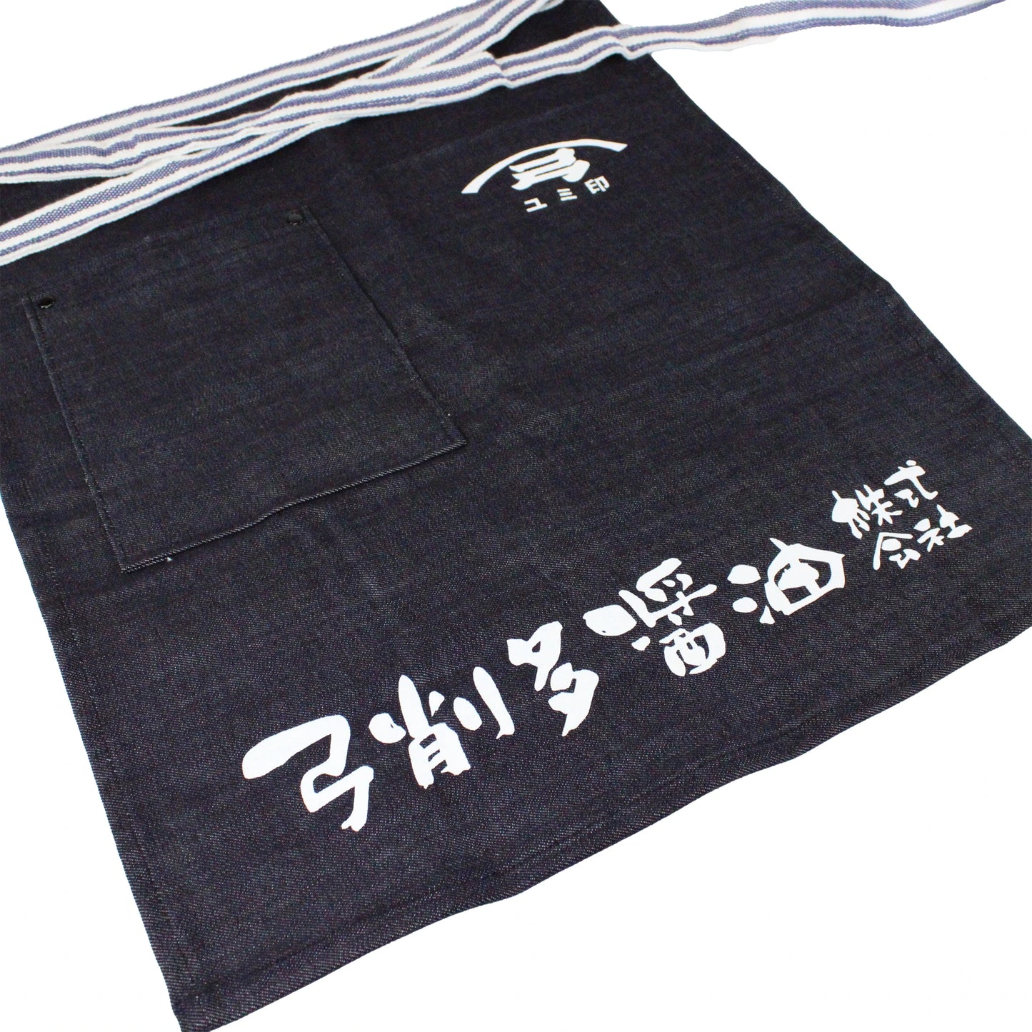 The Yugeta Shoyu Apron is a dark blue denim apron with bold white kanji and logo, a spacious front pocket, and striped waist ties—combining Japanese heritage and practical style.