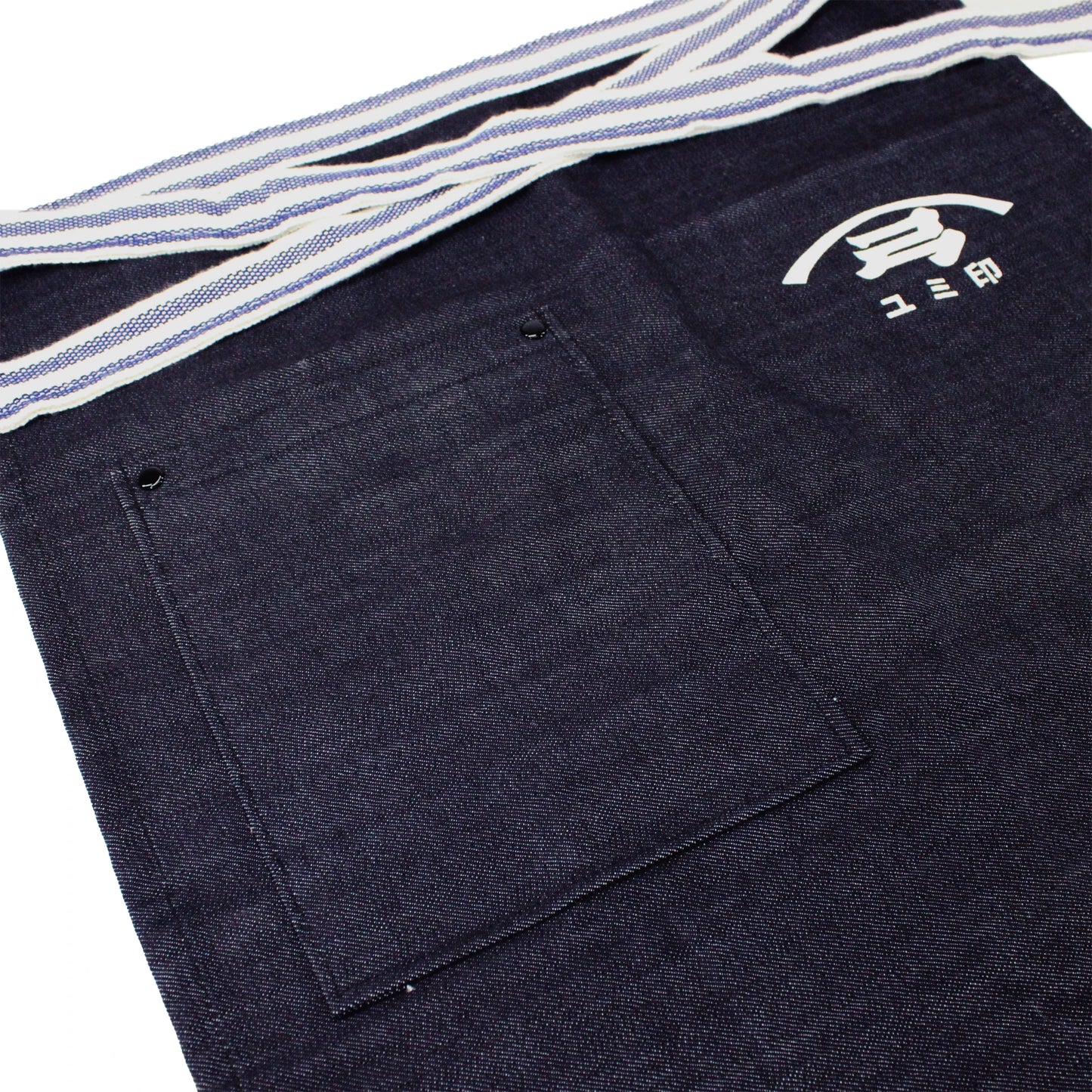 
                  
                    The Yugeta Shoyu Apron is a dark denim kitchen apron with a large front pocket, white logo, Japanese characters above the pocket, and a striped waistband—blending Japanese heritage and modern style for any kitchen.
                  
                