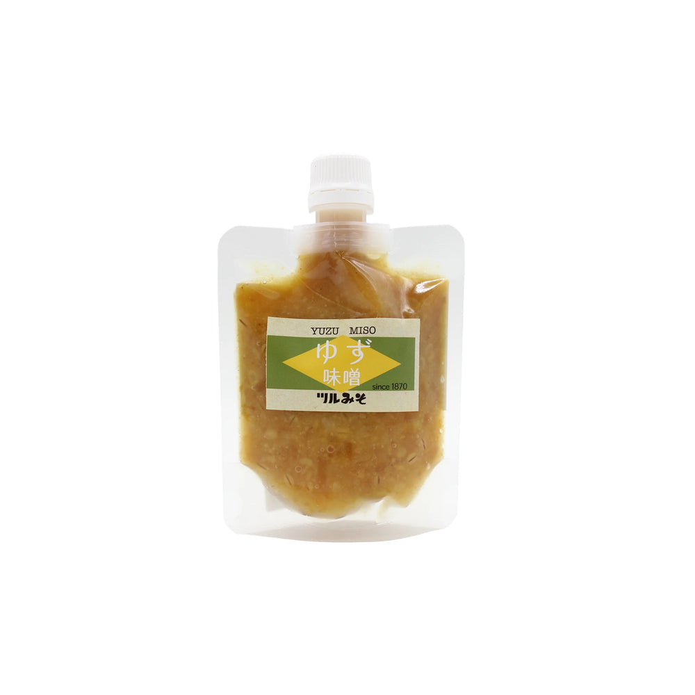 Miso With Yuzu - 150g: This plastic pouch with a spout cap contains yuzu miso paste made with fermented barley. The label features Japanese text and an arrow, making it ideal as a unique salad dressing.