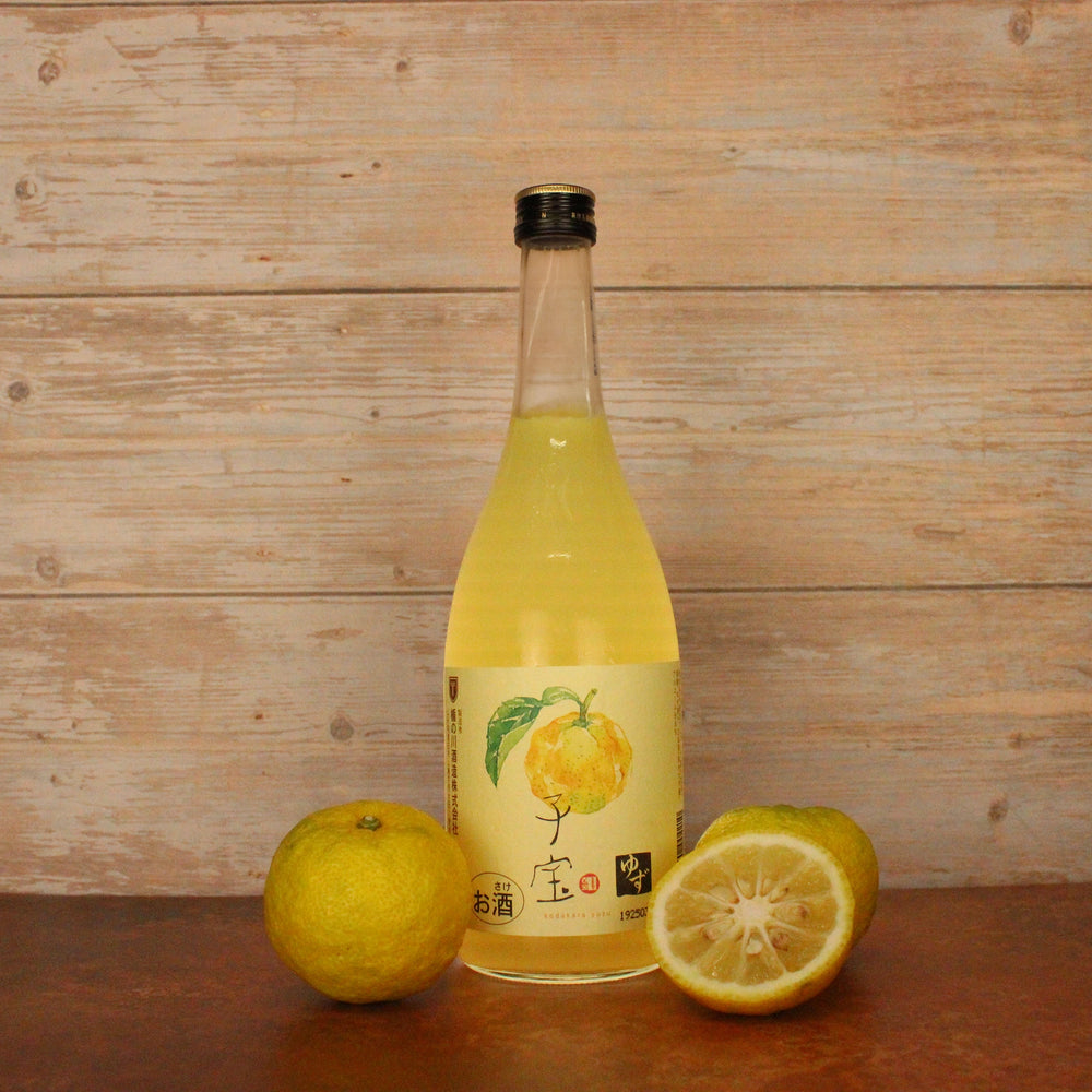 
                  
                    A bottle of Yuzushu - Yuzu with Shochu (720ml) sits on a wooden surface alongside two whole and one halved yuzu, set against a wooden background, showcasing this vibrant Japanese citrus liqueur.
                  
                