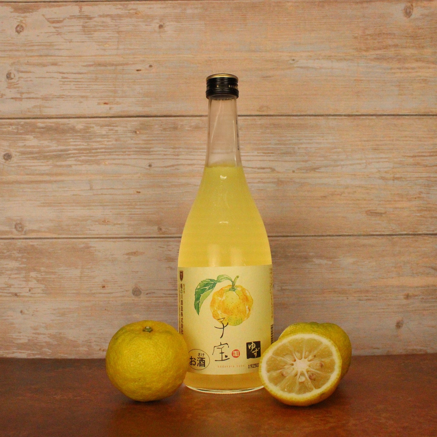
                  
                    A bottle of Yuzushu - Yuzu with Shochu (720ml) sits on a wooden surface alongside two whole and one halved yuzu, set against a wooden background, showcasing this vibrant Japanese citrus liqueur.
                  
                