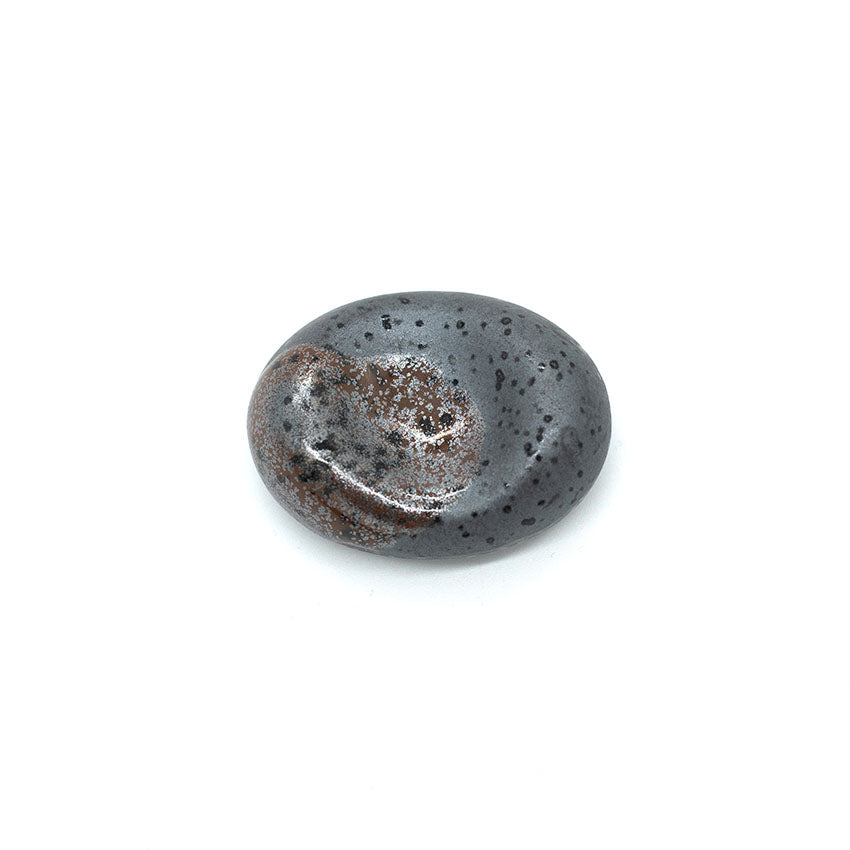 The Chopstick Rest – Pebble Shape Matt Black with Splash features a smooth, oval design with brown and white speckles, offering an elegant table accessory or chopstick holder, displayed against a white background.