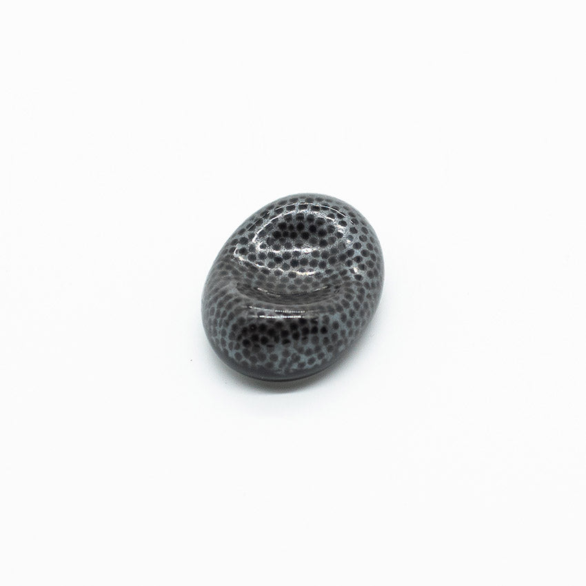 The Chopstick Rest - Pebble Shape Fine Dots is an oval black and gray Minoyaki porcelain piece with fine dark spots, perfect as a unique chopstick rest, shown against a plain white background.