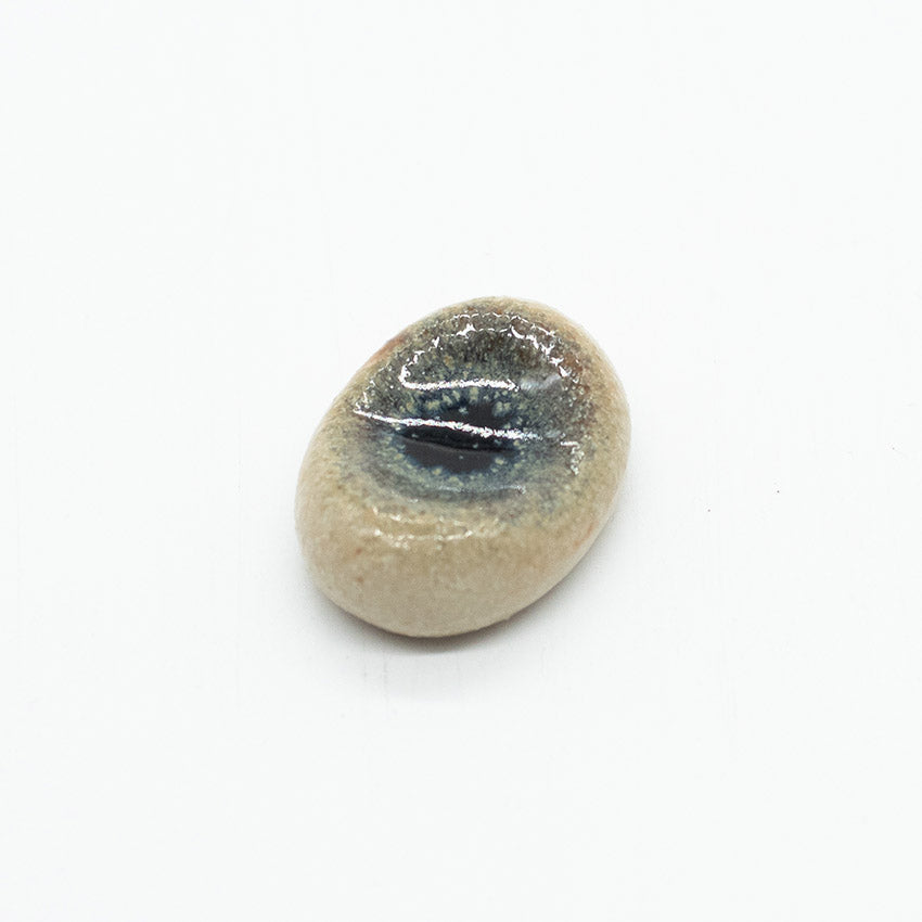 The Chopstick Rest - Pebble Shape Marble features a handmade, oval ceramic design with a glossy dark blue center, elegantly displayed on a plain white background.