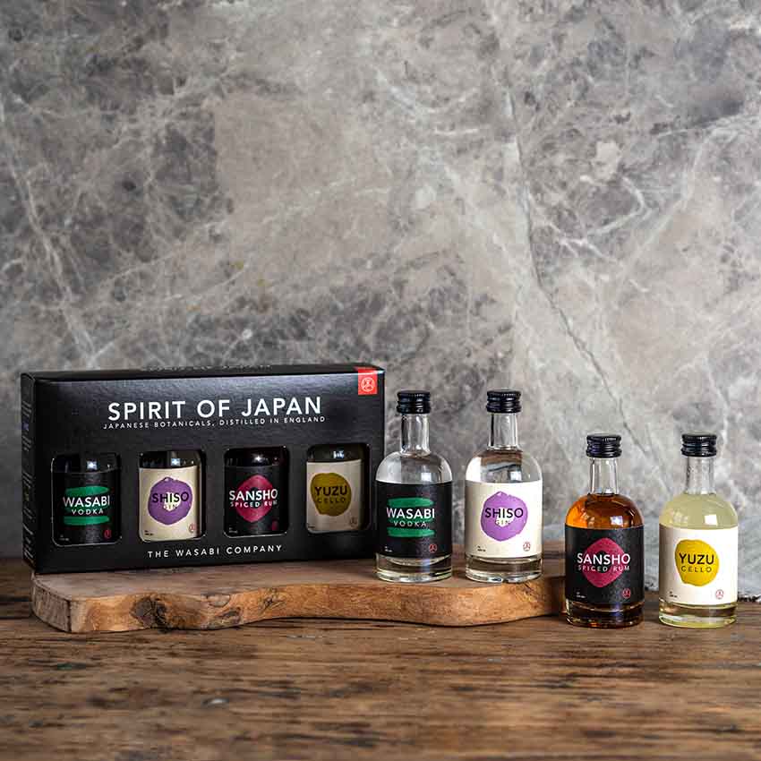 
                  
                    The Spirit of Japan – 4 x 5cl gift set features four small bottles of Japanese craft spirits, each with unique labels, displayed on a wooden board with a grey marble backdrop—an ideal alcohol gift for enthusiasts.
                  
                