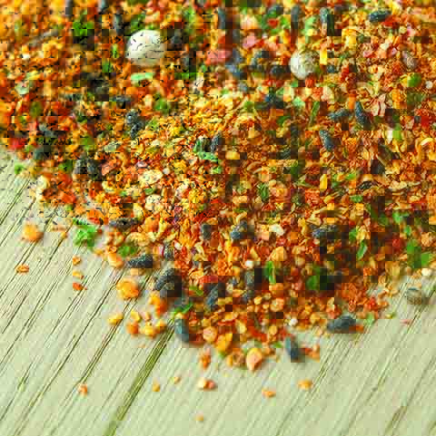 
                  
                    A close-up of Wasabi Label Togarashi Shichimi Spice Mix showcases a vibrant blend of Japanese spices, with visible herbs and peppercorns scattered across a wooden surface.
                  
                