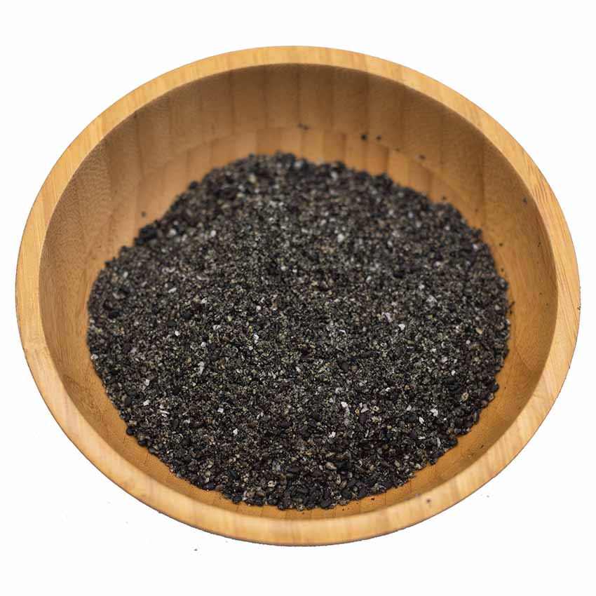 
                  
                    A wooden bowl holds coarse, dark black grains, likely Wadaman Organic Gomashio - 50g, a flavour-boosting sesame seed condiment.
                  
                