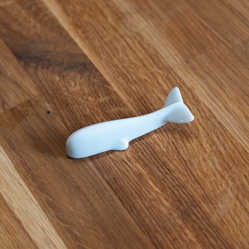 
                  
                    The Whale Chopstick Rest - White is a small, whale-shaped porcelain chopstick rest crafted in traditional Minoyaki style, shown here on a wooden surface.
                  
                